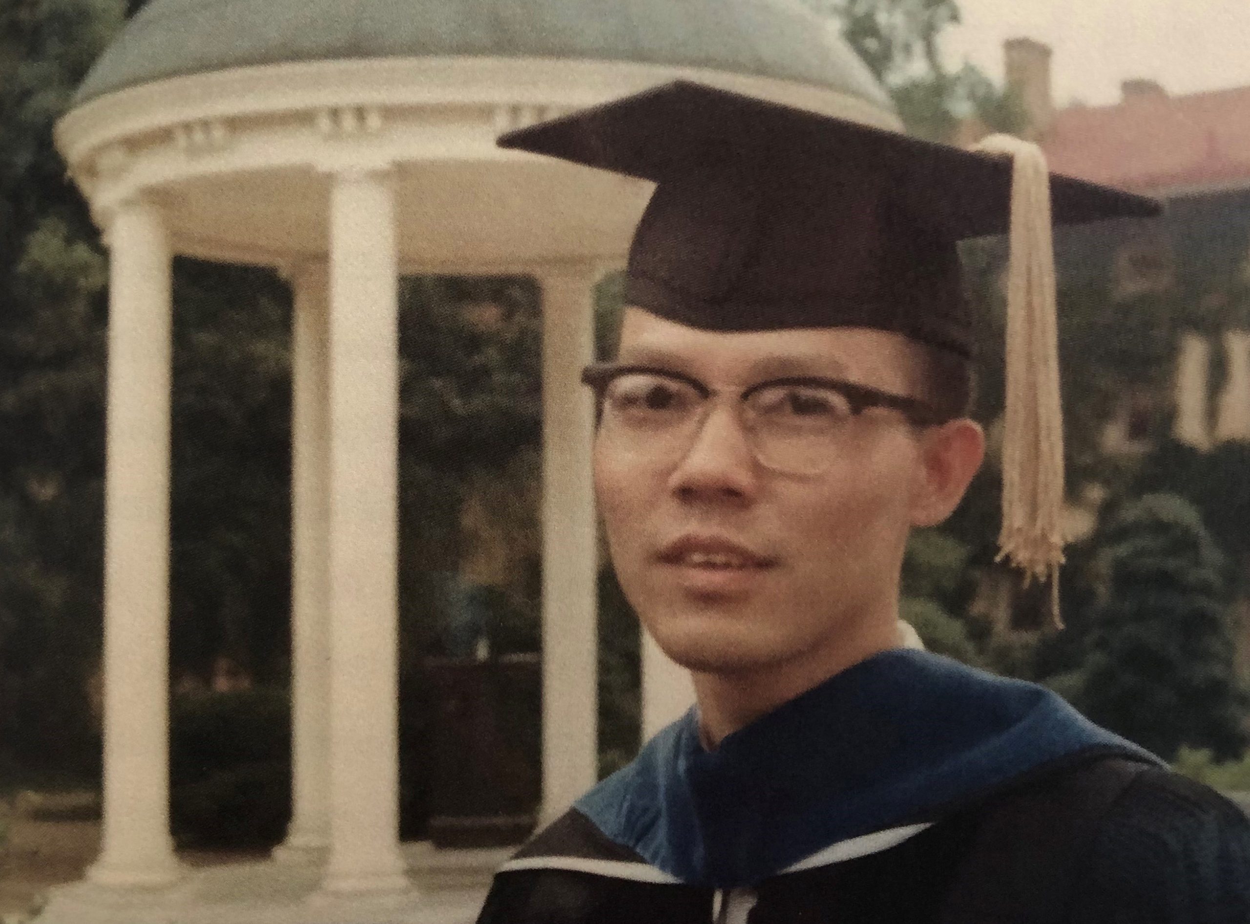 Cliff Huang poses by the Old Well to commemorate the earning of his doctorate from UNC-Chapel Hill in 1968.