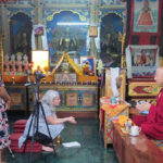 Leve and cultural heritage activist Alina Tamrakar interview the resident monk at Deva Dharma Mahavihar, a Buddhist monastery located in front of the stupa. (photo by Alok Tamrakar)