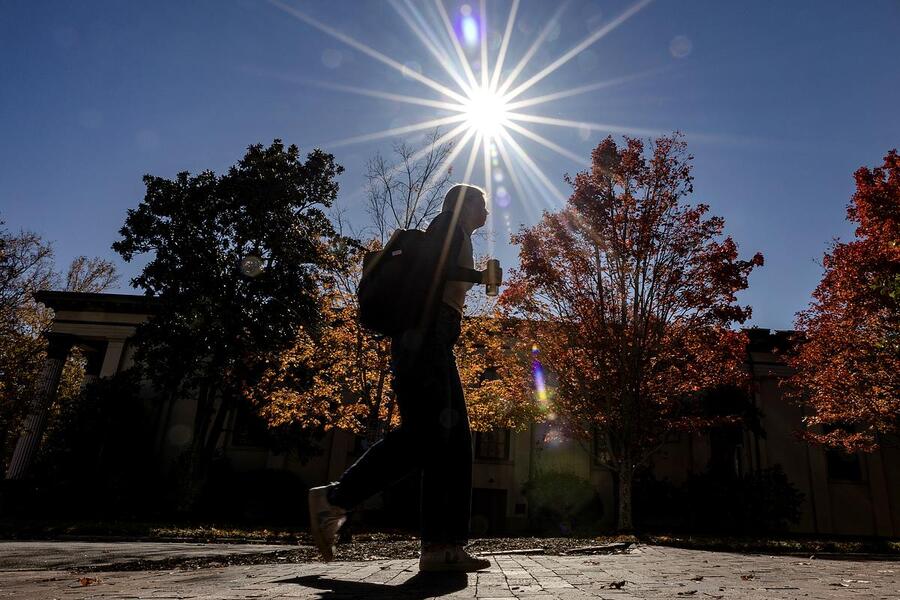 UNC student walking across campus on a fall day.